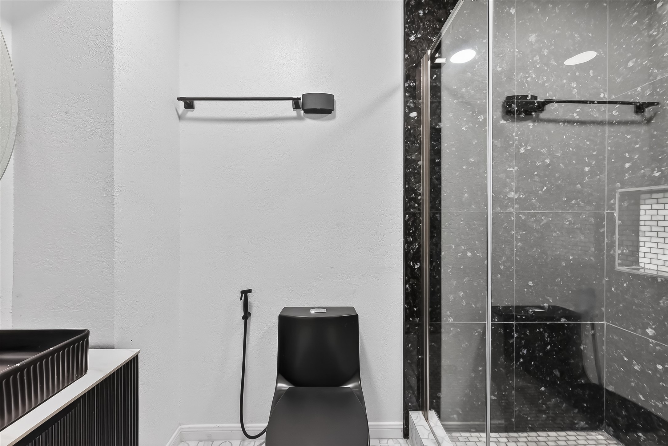1311 Rene Court Sugar Land, TX 77479 - Photo 39 of 45 Modern bathroom featuring a sleek black toilet, a stylish black-tiled shower with glass doors, and contemporary fixtures.
