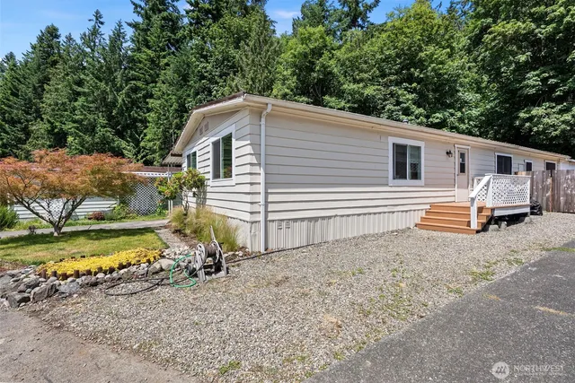 a backyard of a house with large trees and wooden fence
