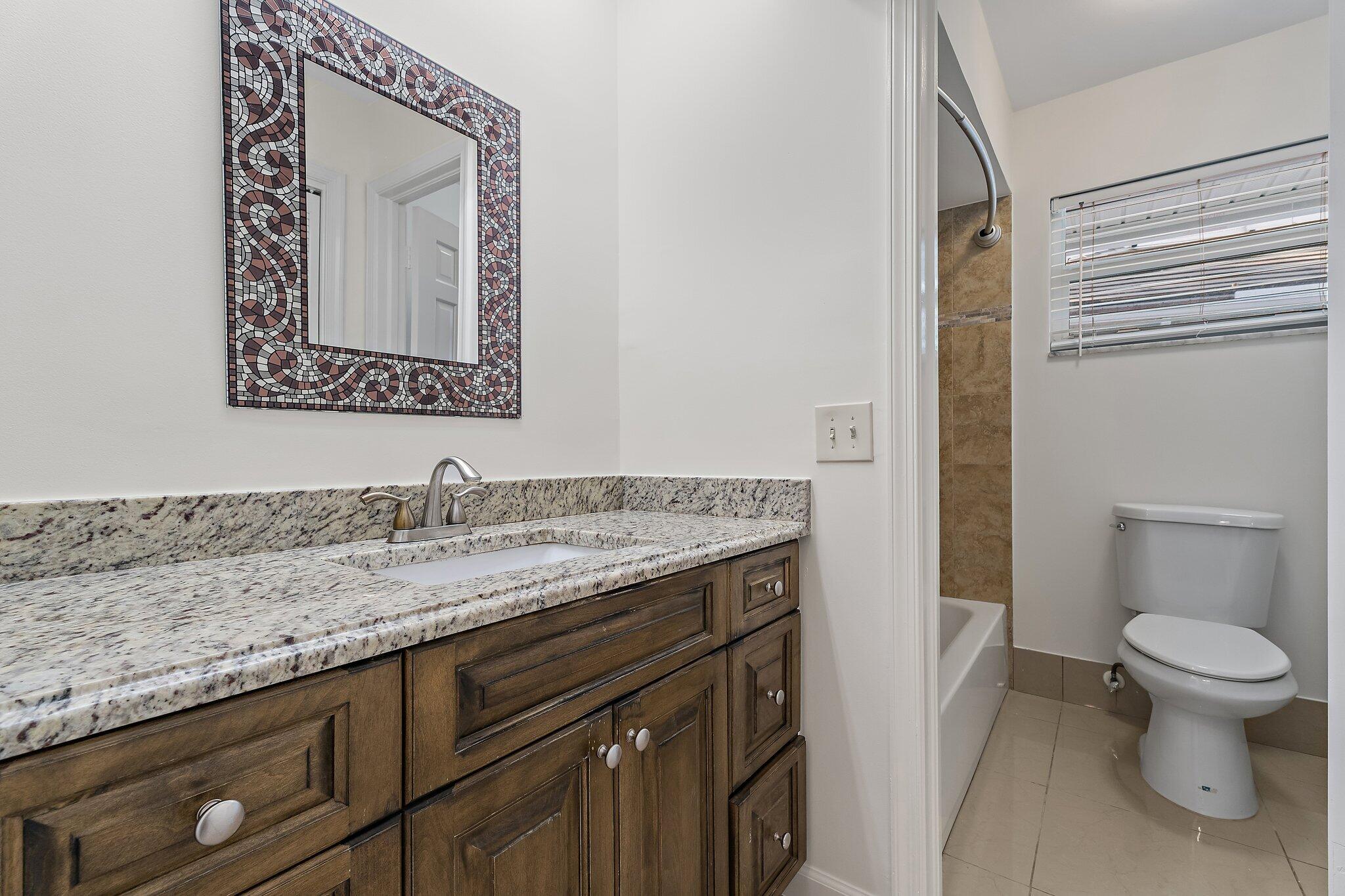 18799 Rio Vista Drive Jupiter, FL 33469 - Photo 34 of 58 a bathroom with a granite countertop sink vanity mirror and toilet