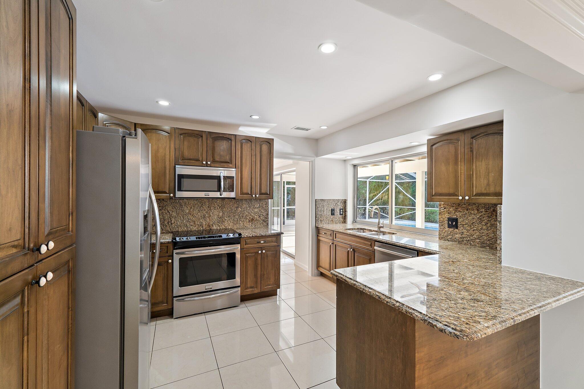 18799 Rio Vista Drive Jupiter, FL 33469 - Photo 10 of 58 a kitchen with stainless steel appliances granite countertop a sink stove and refrigerator