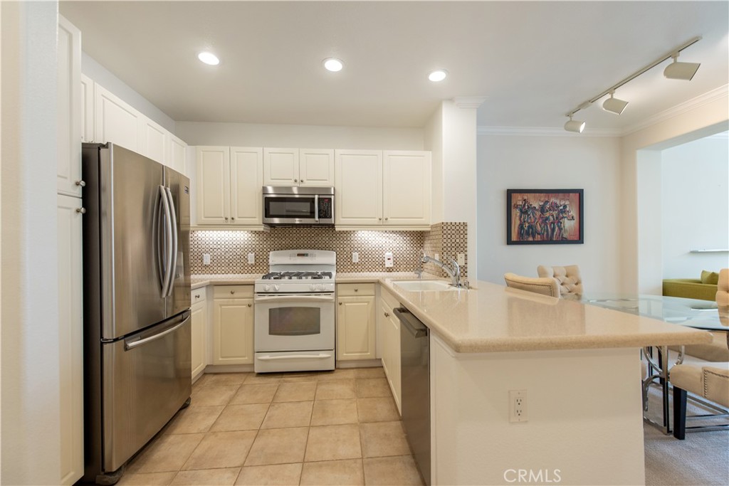 3261 Watermarke Place Irvine, CA 92612 - Photo 2 of 31 a kitchen with a sink a refrigerator and a stove top oven with wooden floor