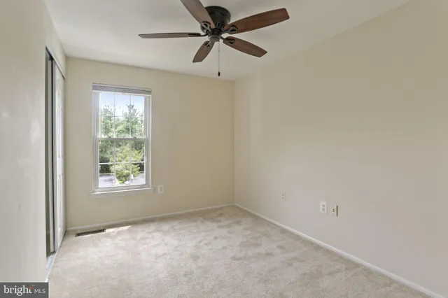 an empty room with a window and a fan