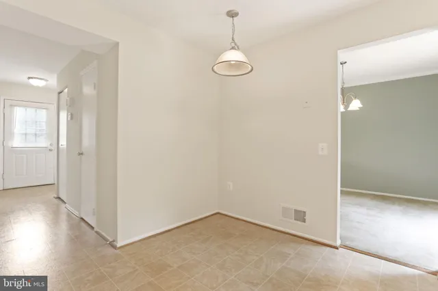 an empty room with chandelier fan and windows