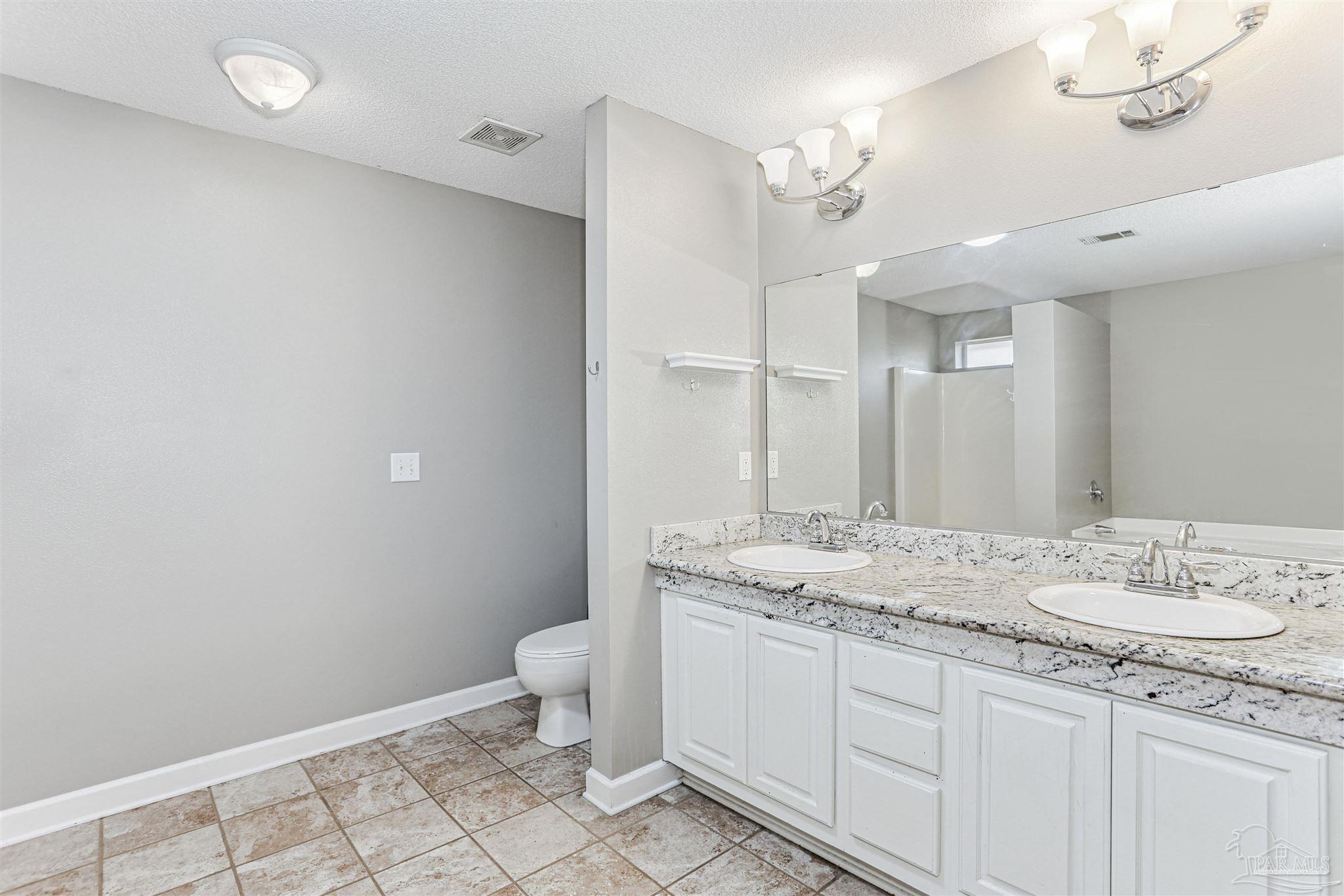 1062 Joaquin Road Pensacola, FL 32506 - Photo 26 of 42 a bathroom with a granite countertop sink a toilet and a mirror