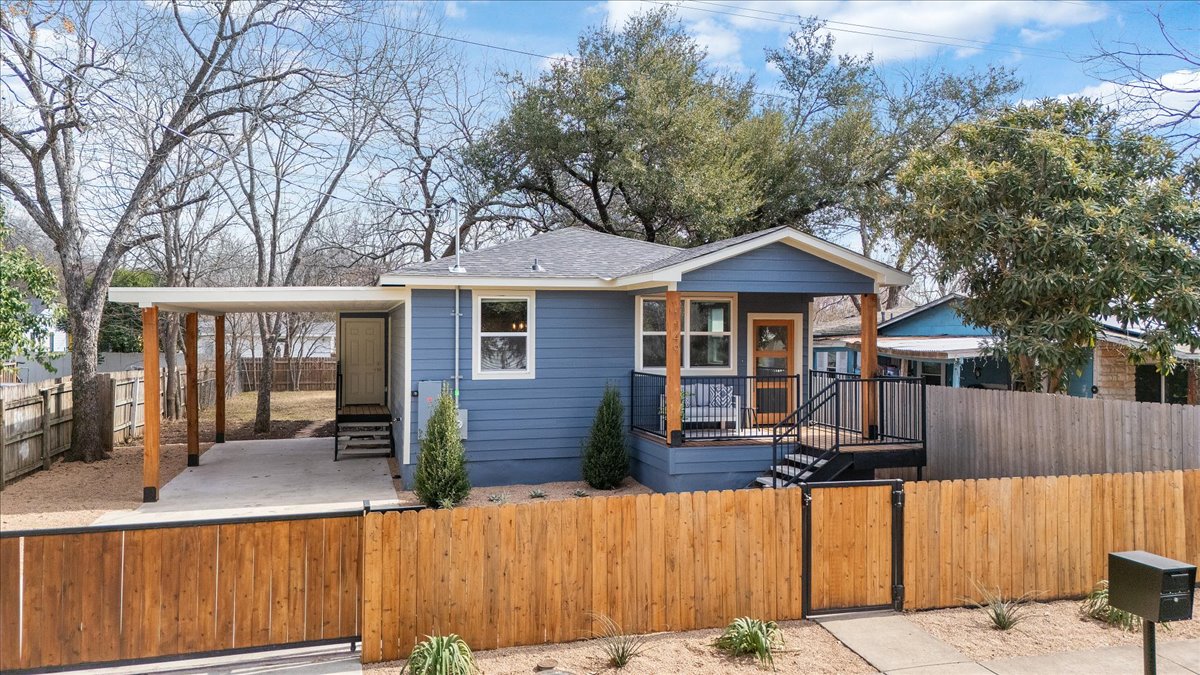 Bungalow-style house featuring a fenced front yard, a gate, a porch, and roof with shingles