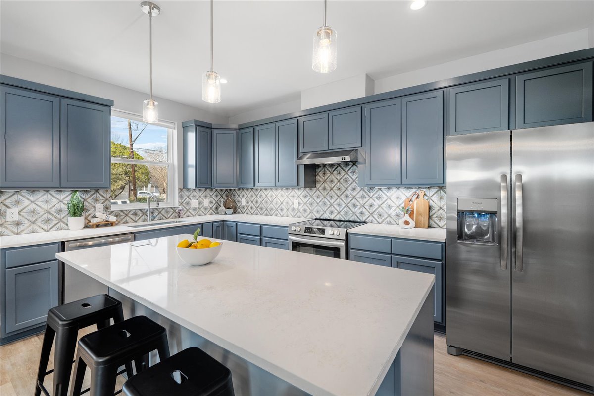 1149 Ebert Avenue, Unit D Austin, TX 78721 - Photo 9 of 34 Kitchen featuring stainless steel appliances, pendant lighting, a kitchen bar, a center island, and blue cabinetry