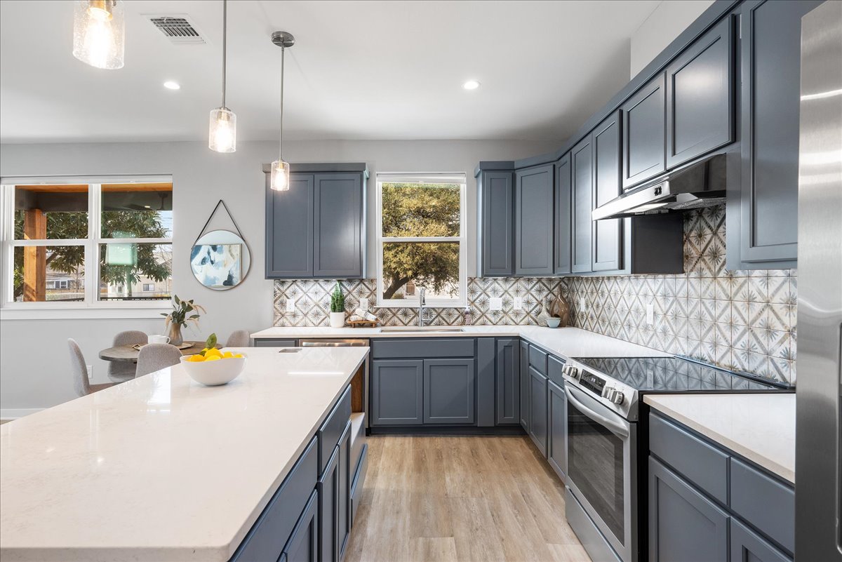 1149 Ebert Avenue, Unit D Austin, TX 78721 - Photo 10 of 34 Kitchen featuring stainless steel appliances, decorative light fixtures, a center island, light wood-type flooring, and light stone countertops