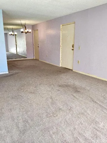 en empty room with windows and chandelier