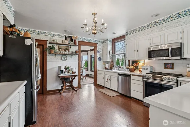 a kitchen with stainless steel appliances granite countertop a refrigerator a stove top oven a sink dishwasher a dining table and chairs with wooden floor