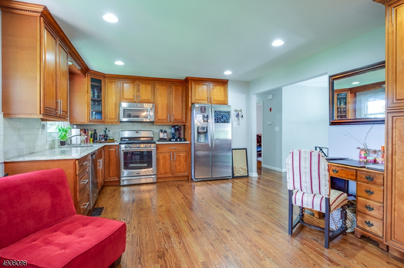 14 Ash Lane Randolph, NJ 07869 - Photo 2 of 22 a kitchen with stainless steel appliances granite countertop a refrigerator a stove top oven and a dining table with wooden floor
