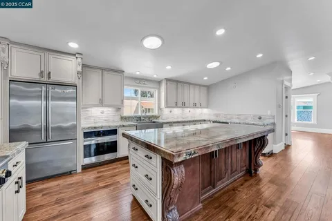 a kitchen with kitchen island a stove a sink and a refrigerator