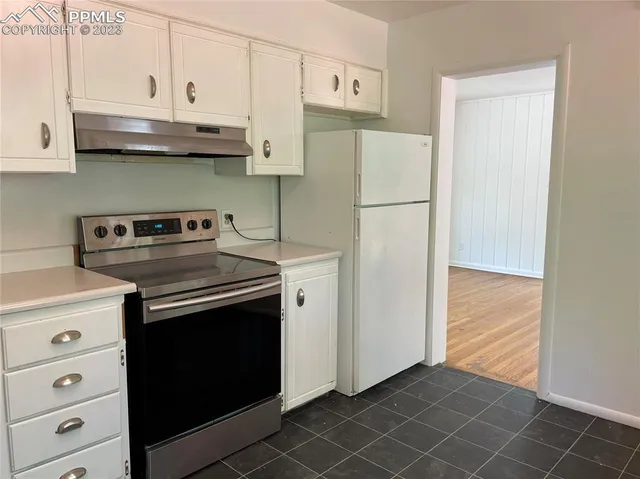a kitchen with stainless steel appliances white cabinets and a refrigerator