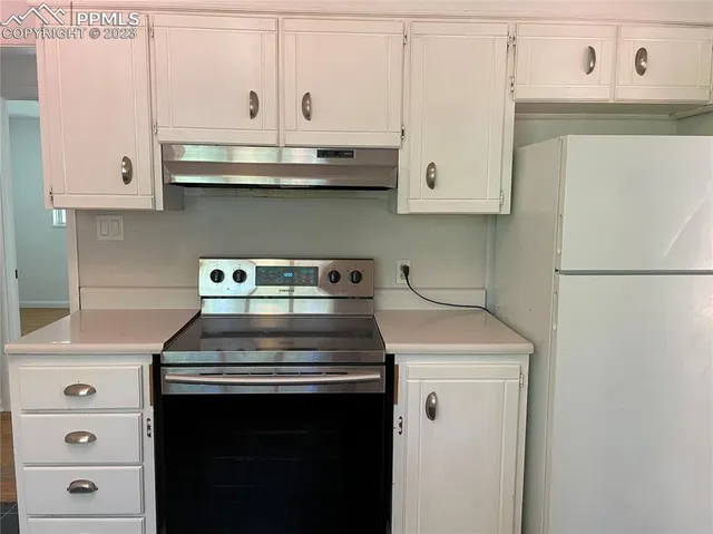 a kitchen with granite countertop white cabinets and white appliances