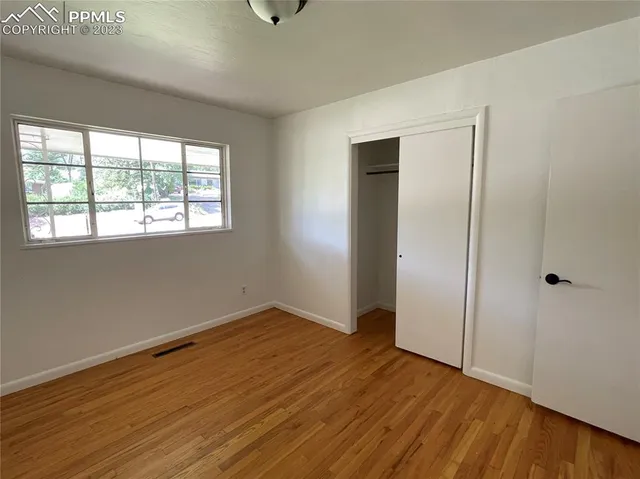 a view of an empty room with wooden floor and a window