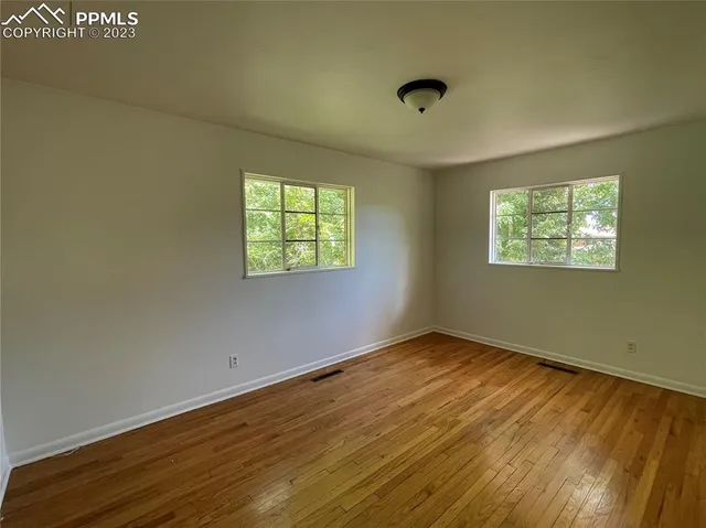 an empty room with wooden floor and windows