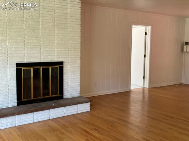 an empty room with wooden floor and a ceiling fan