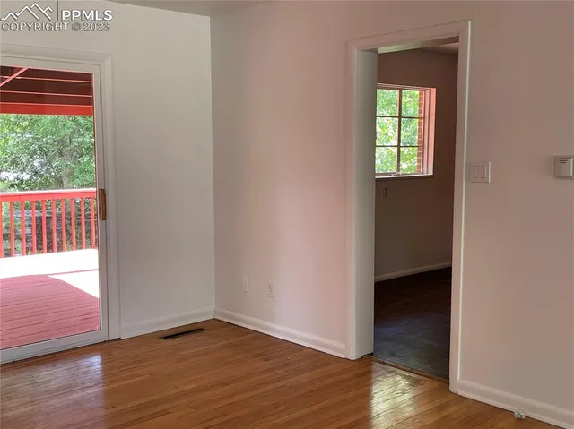 a view of an empty room with wooden floor and a window