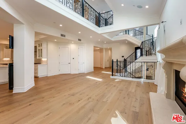 an empty room with wooden floor fireplace and windows