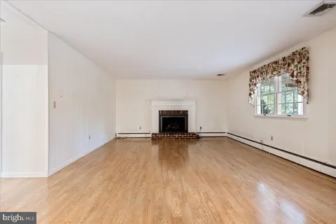 an empty room with wooden floor and fireplace