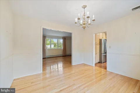 a view of an empty room with wooden floor and kitchen