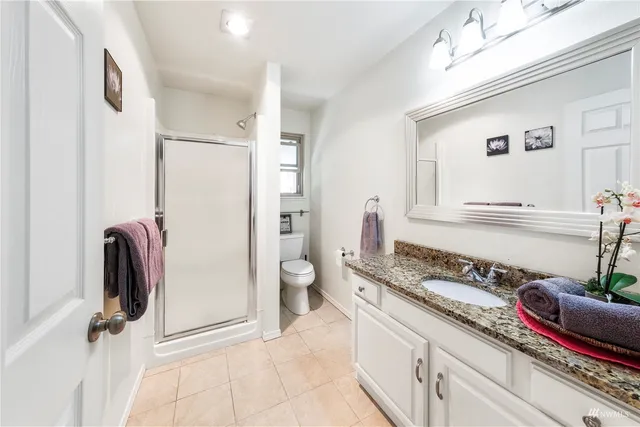 a bathroom with a granite countertop sink a toilet and a mirror