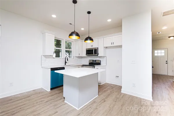 a kitchen with kitchen island a stove a sink a refrigerator and a wooden floor