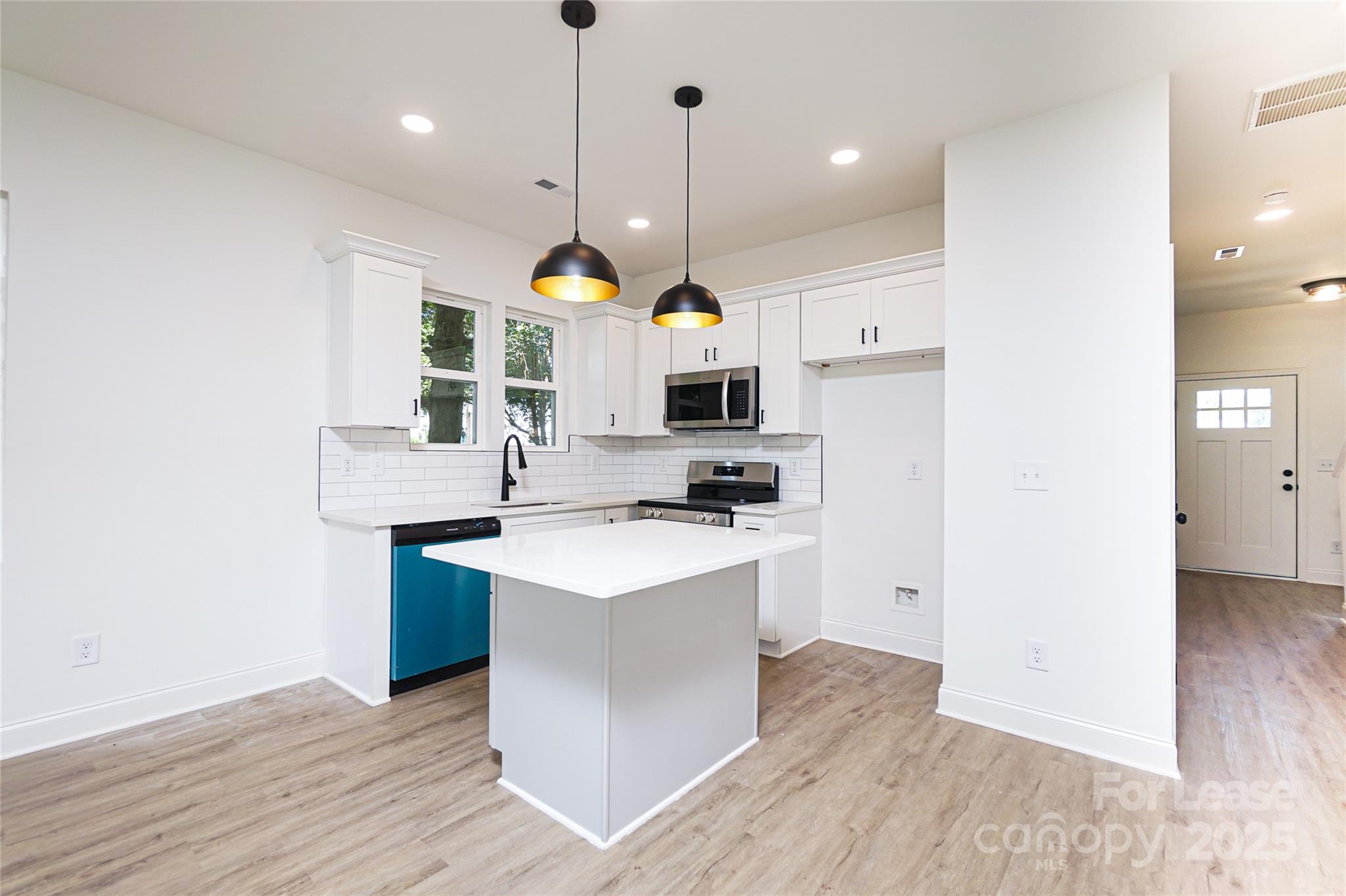 3222 Sam Wilson Road Charlotte, NC 28214 - Photo 6 of 31 a kitchen with kitchen island a stove a sink a refrigerator and a wooden floor