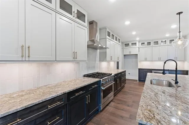 a large kitchen with granite countertop a stove and white cabinets