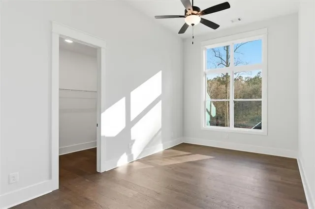 an empty room with wooden floor fan and windows