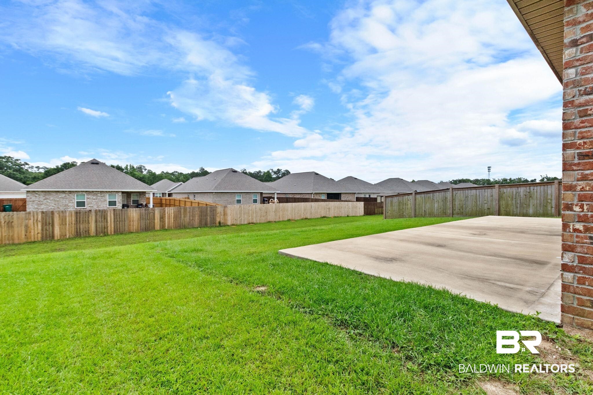 1710 Grouse Street Foley, AL 36535 - Photo 67 of 76 Expansive backyard featuring a large concrete patio, mature green lawn, and full privacy fencing