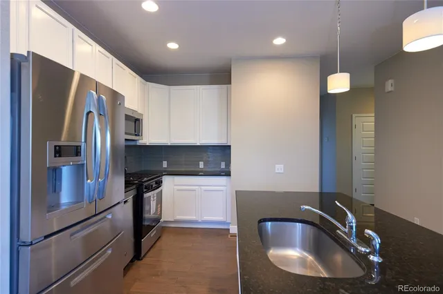 a kitchen with stainless steel appliances granite countertop a sink a refrigerator and a granite counter tops