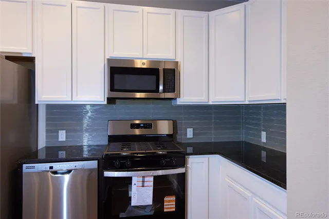a kitchen with stainless steel appliances granite countertop white cabinets and stove