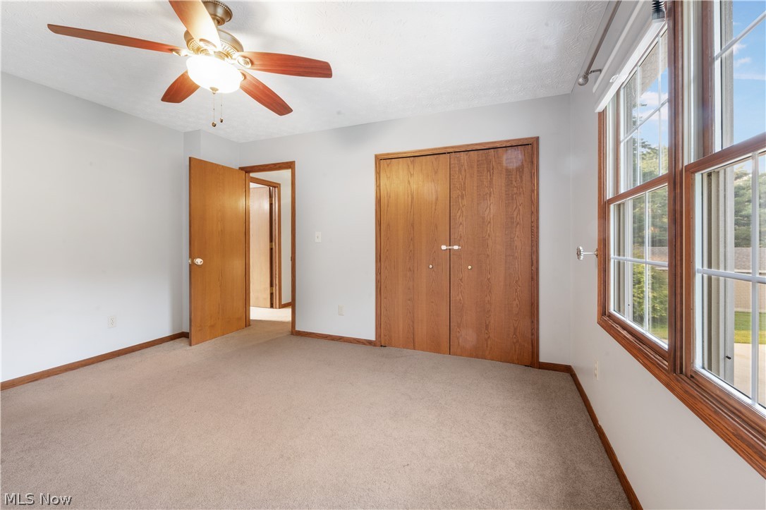 1239 Congress Lake Road Mogadore, OH 44260 - Photo 22 of 35 Unfurnished bedroom featuring light carpet, a closet, and ceiling fan