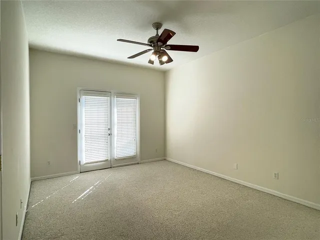 an empty room with a chandelier fan and windows