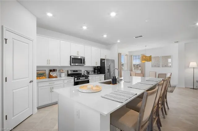 a kitchen with stainless steel appliances granite countertop a refrigerator a stove a sink a dining table and chairs with wooden floor