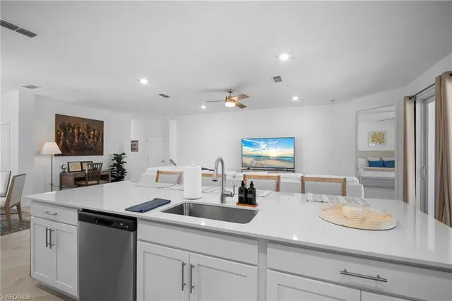 a kitchen with a sink dishwasher a stove and white cabinets with wooden floor