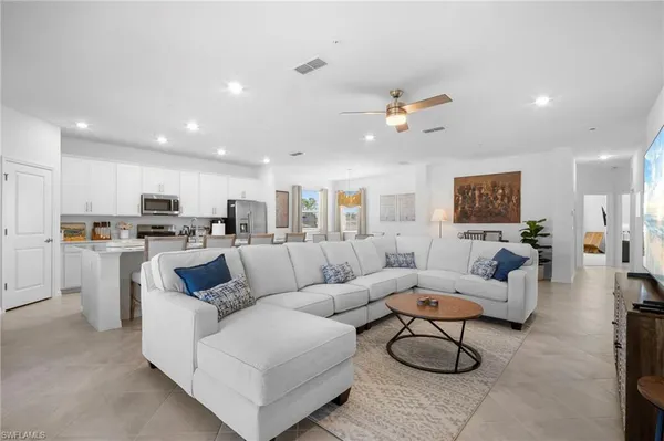 a living room with furniture kitchen view and a chandelier