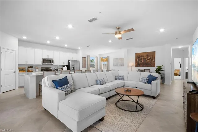 a living room with furniture kitchen view and a chandelier
