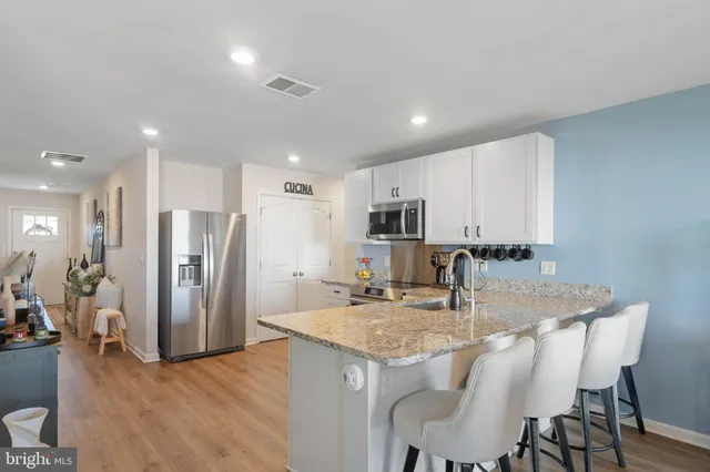 a kitchen with stainless steel appliances granite countertop a kitchen island a stove a table and chairs