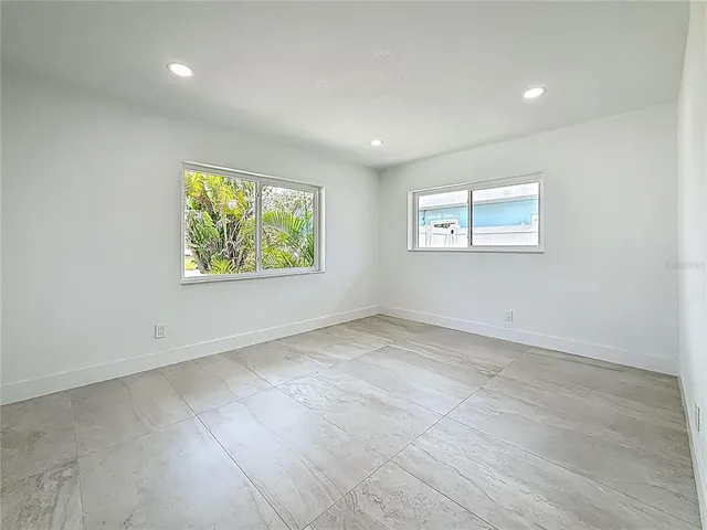 a bedroom with a bed a mirror on dresser and a window
