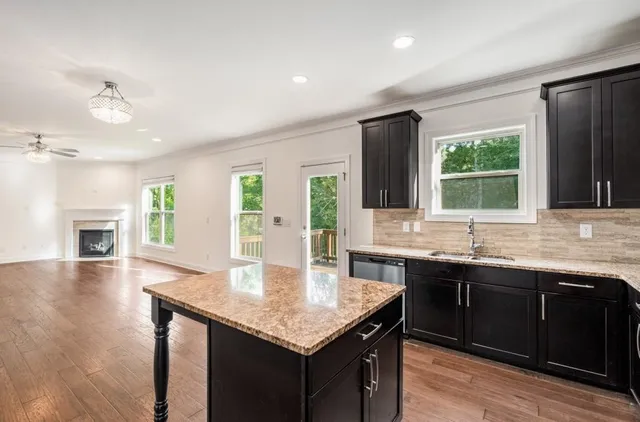 a kitchen with granite countertop kitchen island a sink stove and wooden floor
