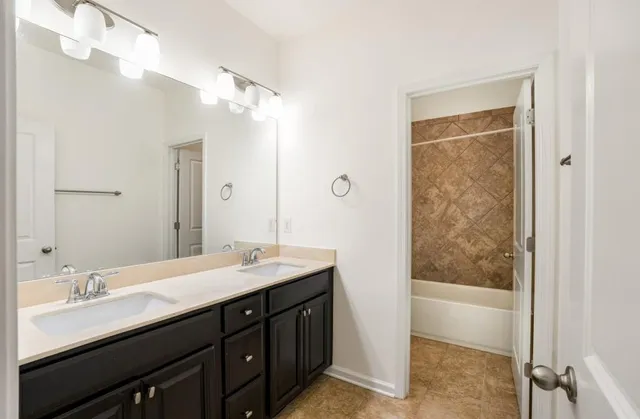 a bathroom with a double vanity sink a mirror and a bathtub