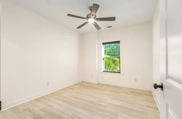 an empty room with a window and a fan