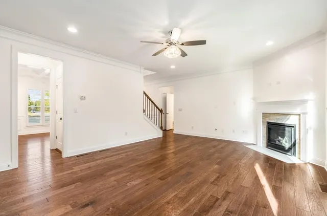 a view of an empty room with wooden floor fireplace and a window