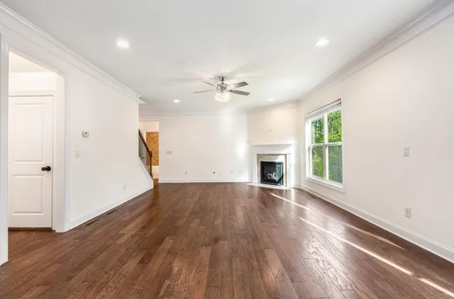 an empty room with wooden floor fireplace and windows