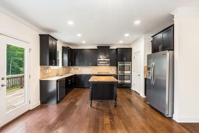 a large kitchen with a center island wooden floor stainless steel appliances and windows