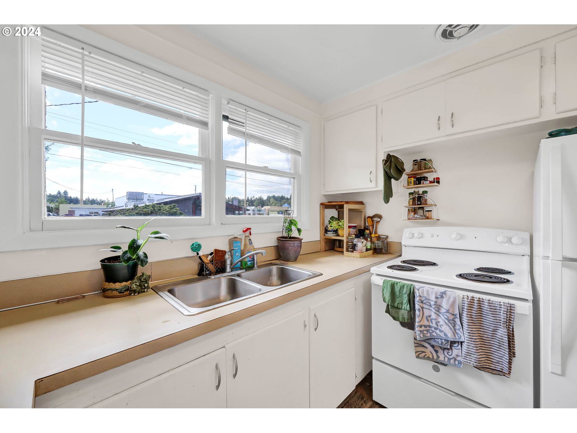 2915-2925 Oak Street Eugene, OR 97405 - Photo 32 of 42 a kitchen with stainless steel appliances a sink a stove and white cabinets next to a window