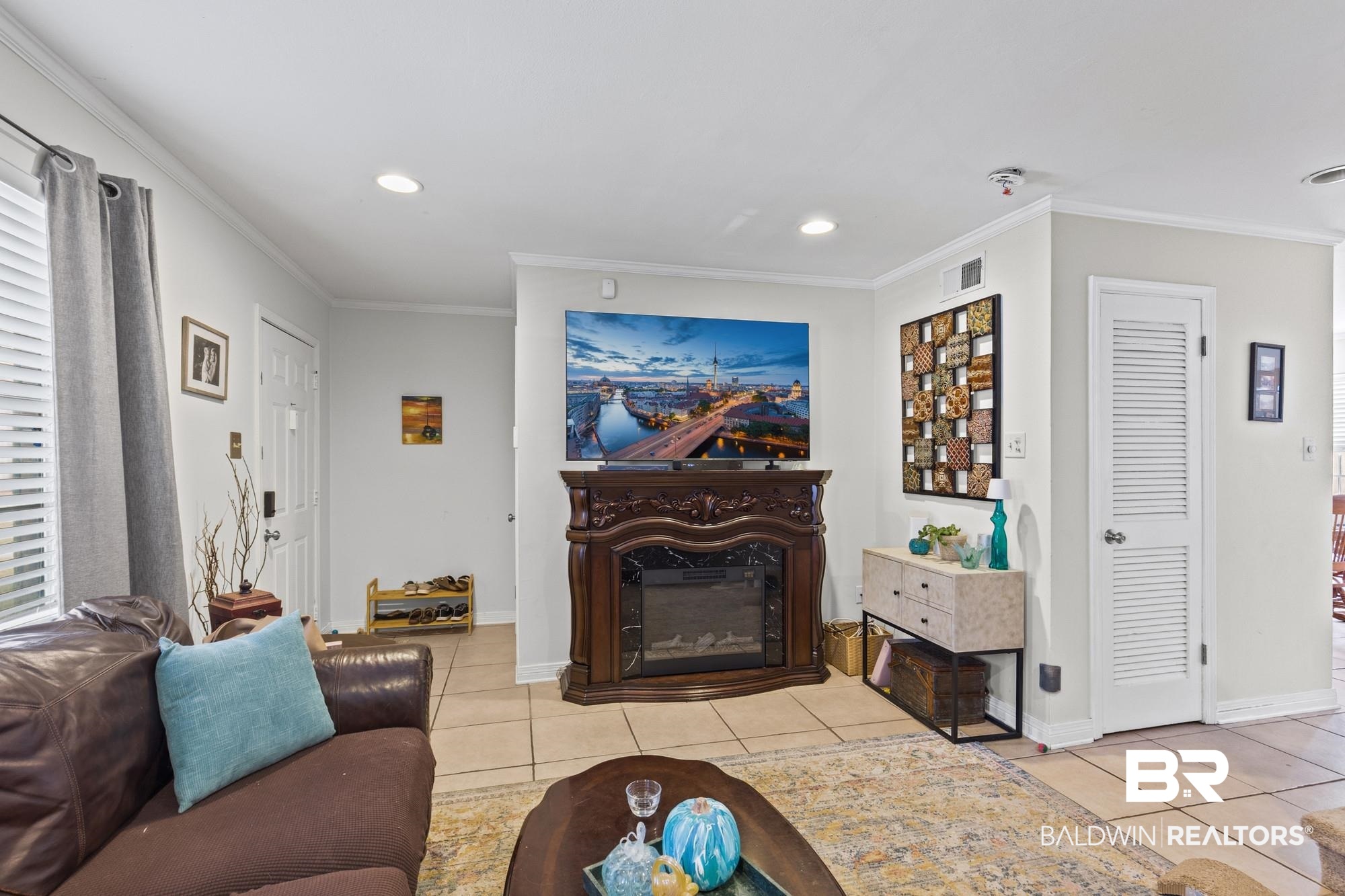 114 Du Rhu Drive, Unit A Mobile, AL 36608 - Photo 4 of 14 Living room featuring a glass covered fireplace, light tile patterned floors, recessed lighting, and crown molding