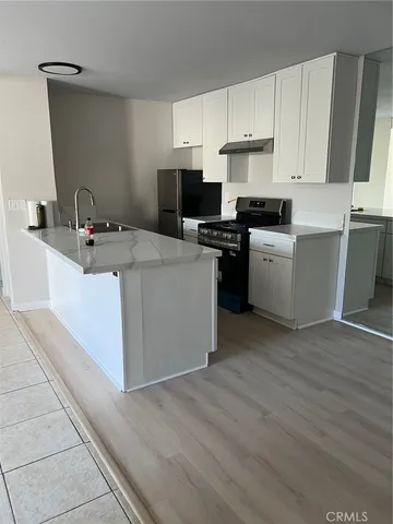 a kitchen with a sink a stove top oven and white stainless steel appliances