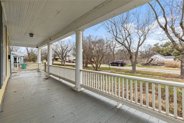 a view of a porch with wooden floor and wooden fence